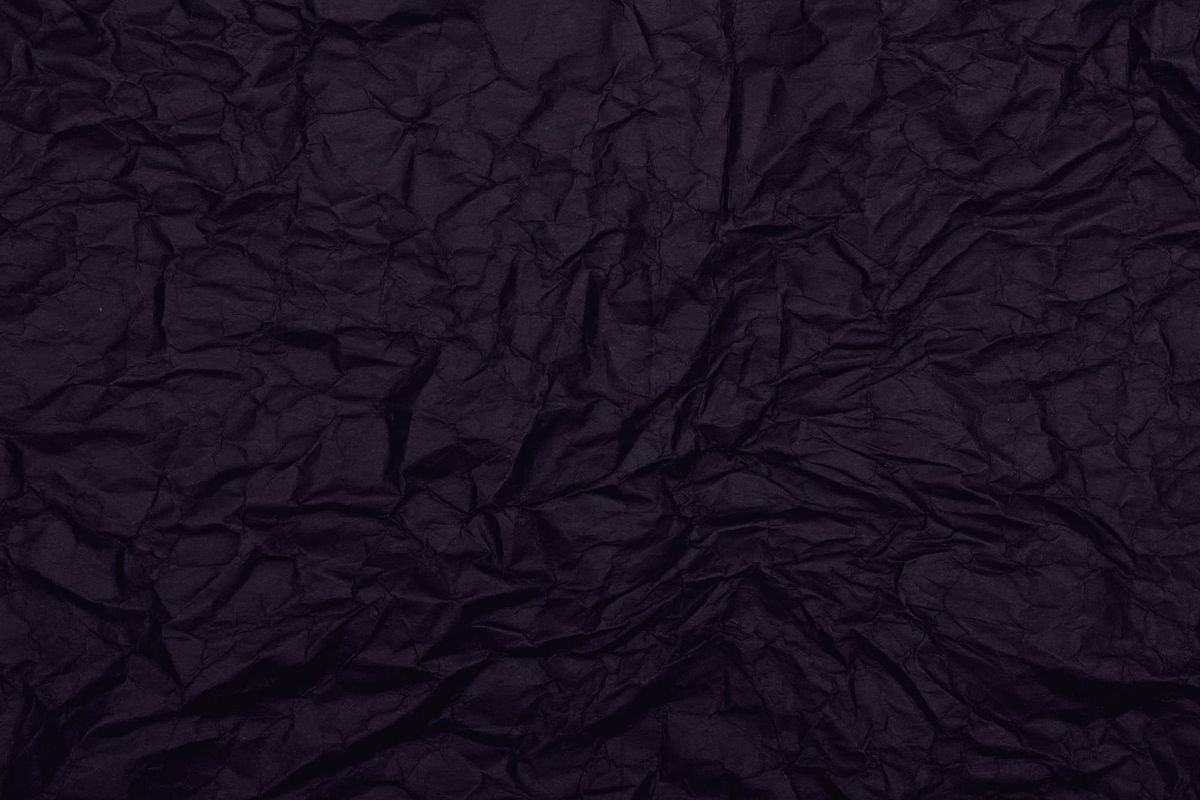 Dark crumpled paper, lit from one side