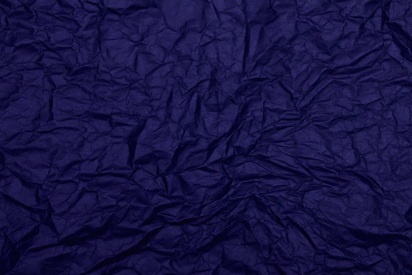 A sheet of deep indigo paper crushed and reopened, every crease still visible.
