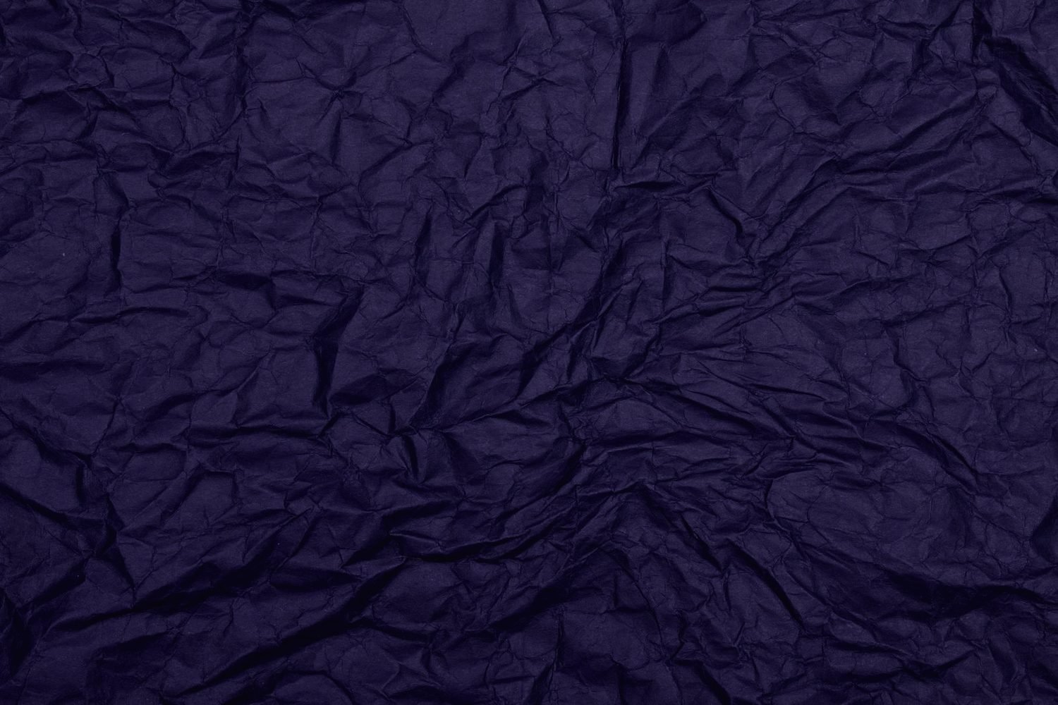 A sheet of deep violet paper crumpled out of shape, lit hard from one side.