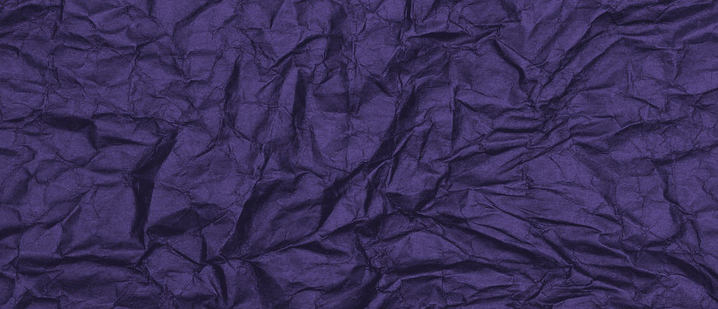 Crumpled violet paper filling the frame, every crease lit