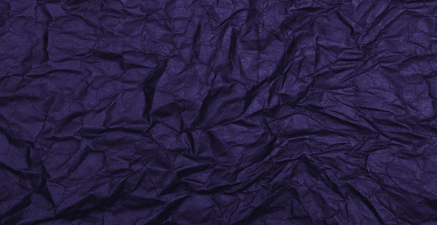 Dark crumpled paper, the creases catching a low light