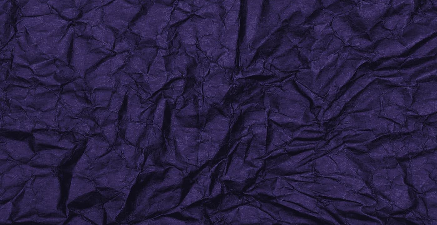 Dark crumpled paper under a low light