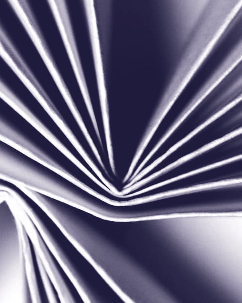 A sheet of paper pleated into a tight fan, lit from one side