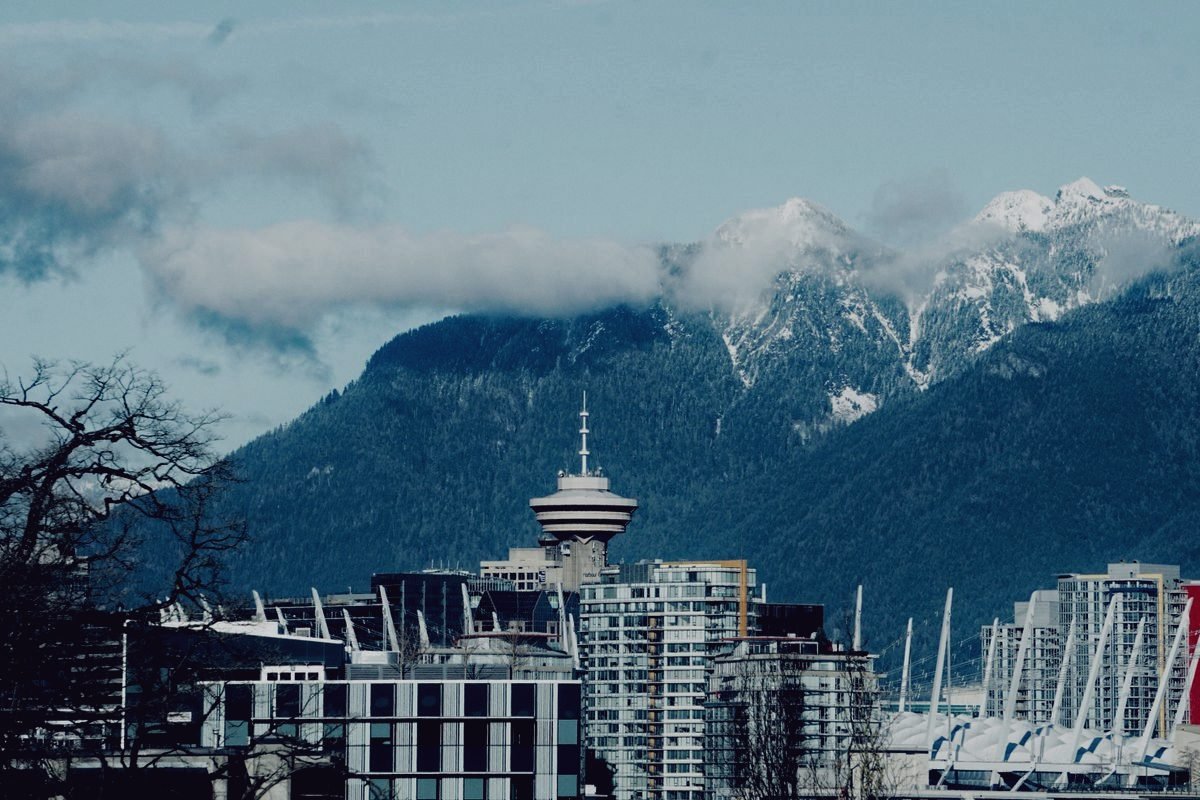 Vancouver towers standing below snow covered mountains under low cloud.