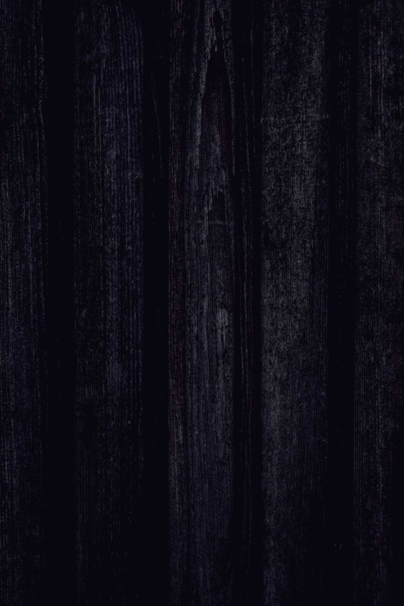 A dark wooden workbench surface, the grain running vertically under low light.